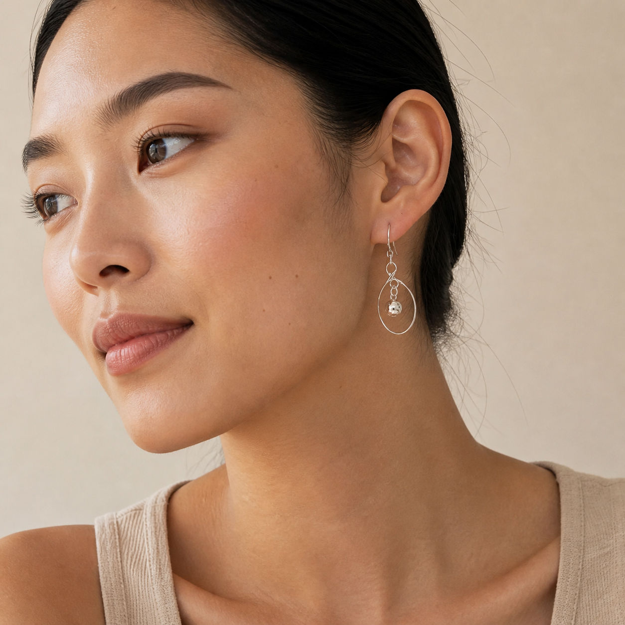 Woman wearing PJ Luxe sterling silver orbit earrings with polished bead