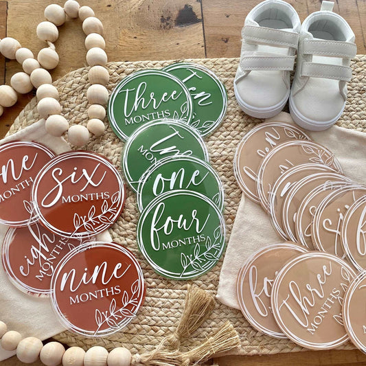 Acrylic baby milestone discs arranged for first-year photographs