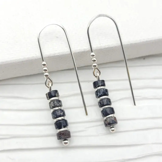 Elegant dangle earrings featuring polished black Jasper stones set in sterling silver, with a sleek design that elegantly frames the face. Ideal for adding a sophisticated touch to any ensemble.