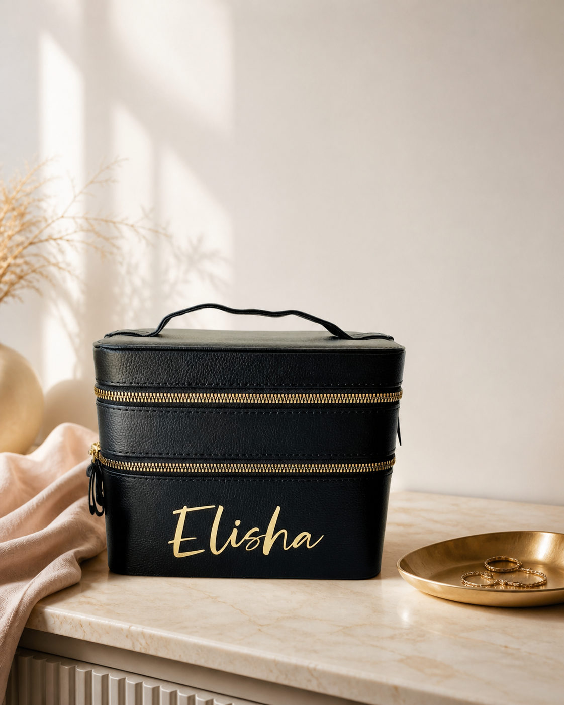 PJ Luxe black personalised travel makeup case with gold zips and Elisha name on an ivory vanity
