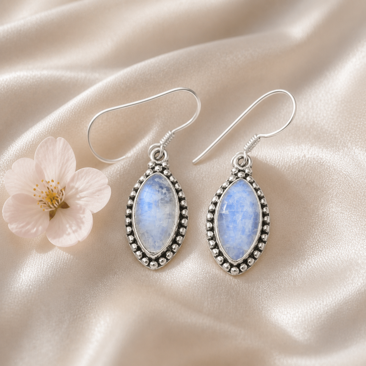 Moonstone teardrop sterling silver earrings styled on champagne satin — PJ Luxe