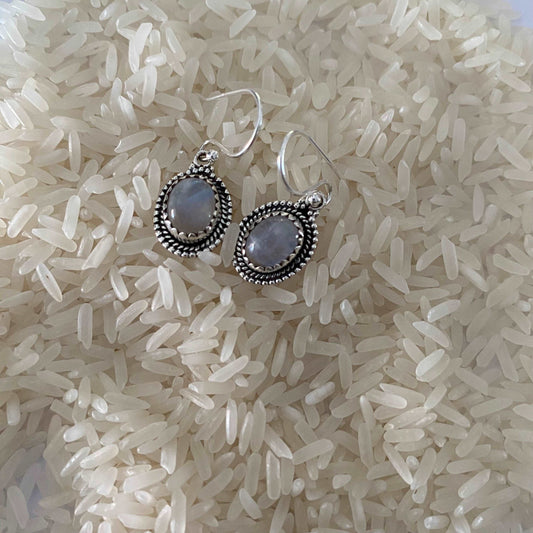 Elegant oval drop earrings crafted from sterling silver, showcasing luminous moonstone gems that gracefully dangle, exuding a serene and enchanting allure.