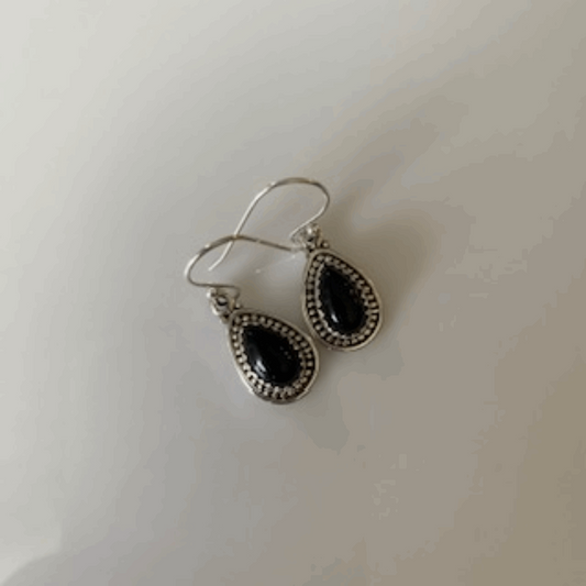 Elegant pair of Classic Black Onyx Teardrop Earrings, showcasing glossy, deep black onyx gemstones elegantly set within polished sterling silver teardrop frames, designed for sophisticated allure.