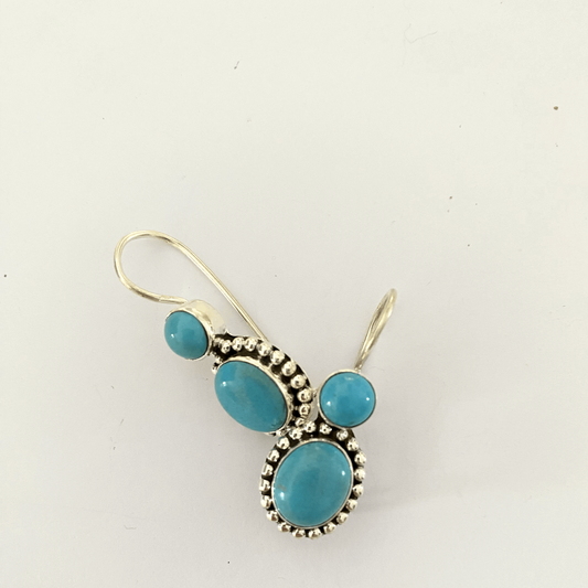 Elegant handcrafted sterling silver earrings, featuring vibrant turquoise stones set in a classic design, embodying timeless beauty and sophistication.