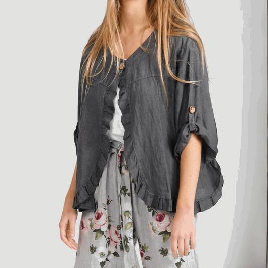 Close-up of a woman wearing the Fifi Linen Jacket in Charcoal with ruched sleeves, open front, and layered over floral pants.