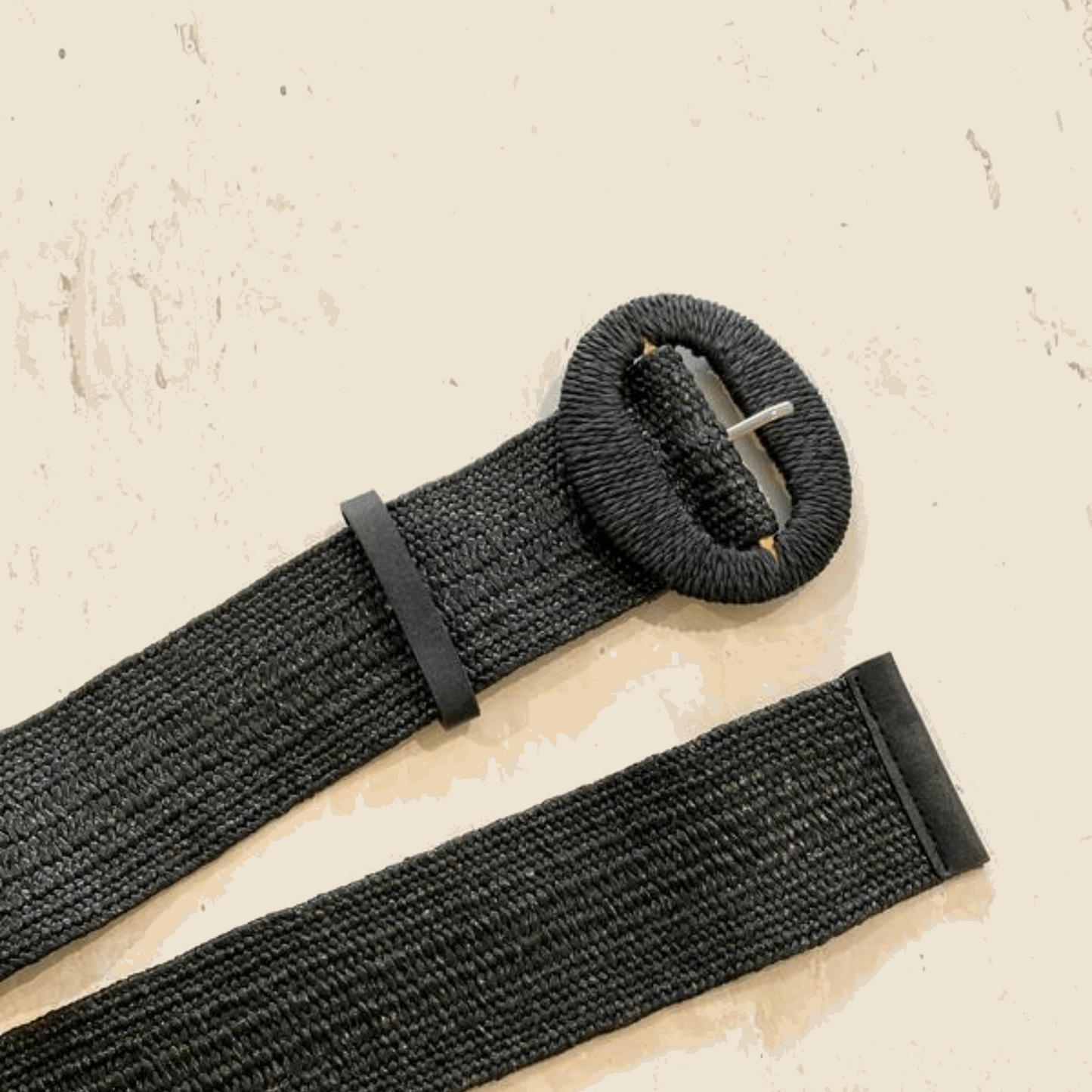 Chic black stretch straw belt featuring a large round buckle, offering a versatile and comfortable fit. Perfect for cinching waists on dresses and blouses, adding a stylish touch to any outfit.