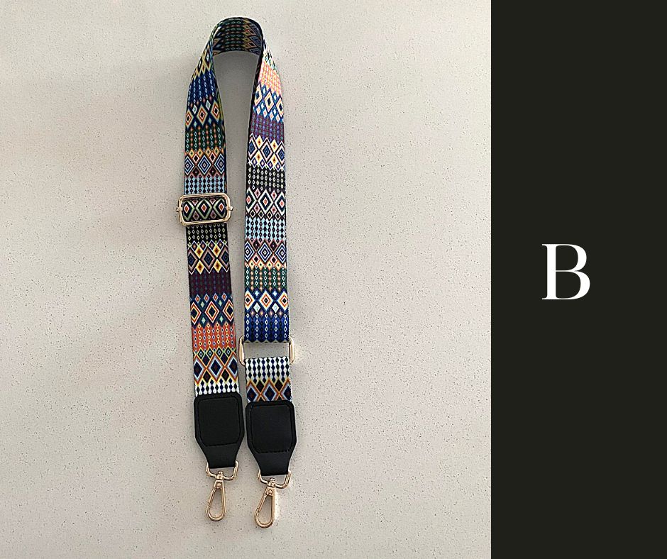 The image showcases a collection of Luxe Bohemian Guitar Style Shoulder Straps laid out horizontally. Each strap is adorned with vibrant, intricate patterns, featuring a mix of geometric shapes and vivid colors that exude a bohemian aesthetic. The straps are finished with sturdy hardware, suggesting a functional yet fashionable accessory designed to complement and enhance a variety of handbags or travel items. The overall presentation is rich and colorful, aligned with a luxurious and eclectic style