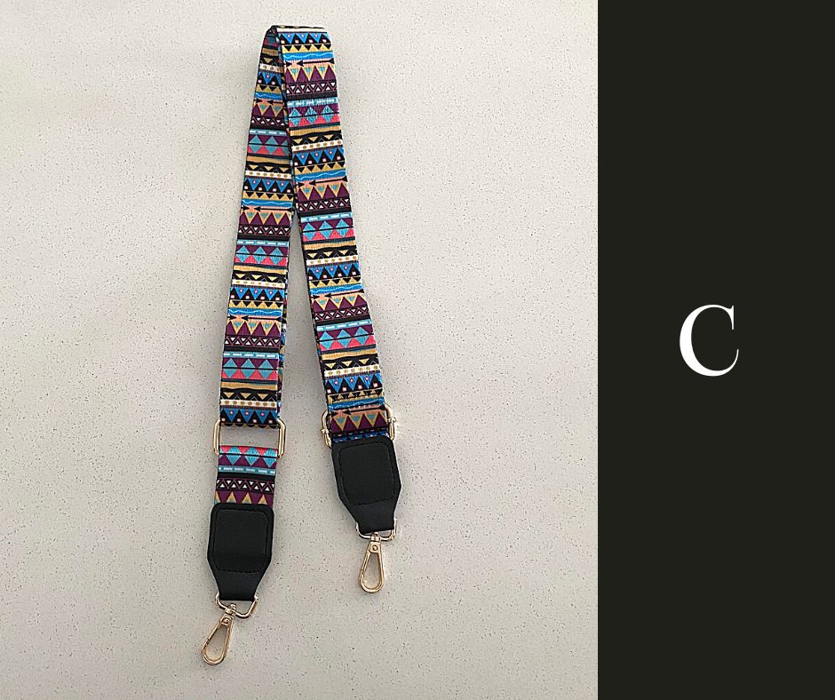 The image showcases a collection of Luxe Bohemian Guitar Style Shoulder Straps laid out horizontally. Each strap is adorned with vibrant, intricate patterns, featuring a mix of geometric shapes and vivid colors that exude a bohemian aesthetic. The straps are finished with sturdy hardware, suggesting a functional yet fashionable accessory designed to complement and enhance a variety of handbags or travel items. The overall presentation is rich and colorful, aligned with a luxurious and eclectic style