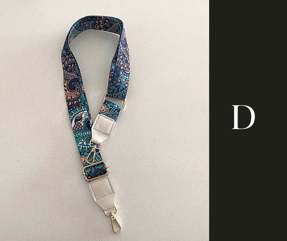 The image showcases a collection of Luxe Bohemian Guitar Style Shoulder Straps laid out horizontally. Each strap is adorned with vibrant, intricate patterns, featuring a mix of geometric shapes and vivid colors that exude a bohemian aesthetic. The straps are finished with sturdy hardware, suggesting a functional yet fashionable accessory designed to complement and enhance a variety of handbags or travel items. The overall presentation is rich and colorful, aligned with a luxurious and eclectic style