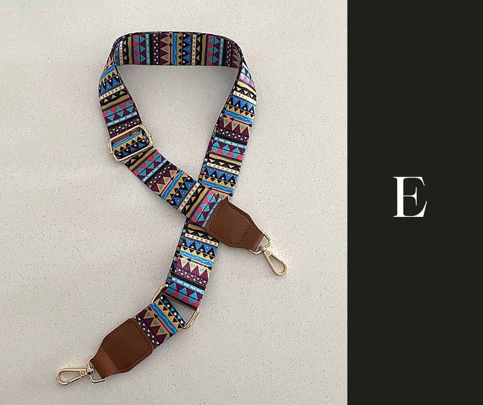 The image showcases a collection of Luxe Bohemian Guitar Style Shoulder Straps laid out horizontally. Each strap is adorned with vibrant, intricate patterns, featuring a mix of geometric shapes and vivid colors that exude a bohemian aesthetic. The straps are finished with sturdy hardware, suggesting a functional yet fashionable accessory designed to complement and enhance a variety of handbags or travel items. The overall presentation is rich and colorful, aligned with a luxurious and eclectic style