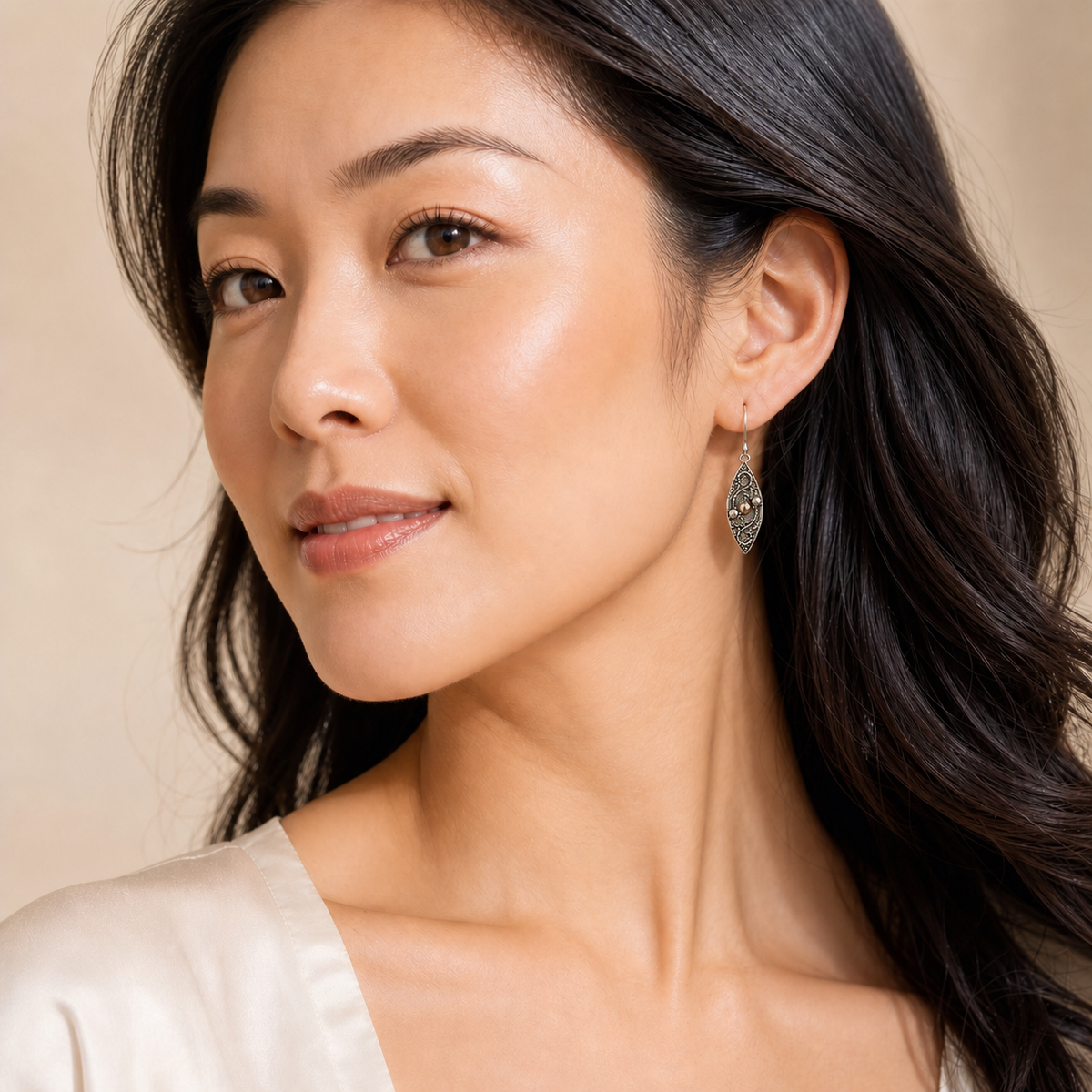 Young adult woman wearing small PJ Luxe sterling silver filigree teardrop earrings with rose gold accents