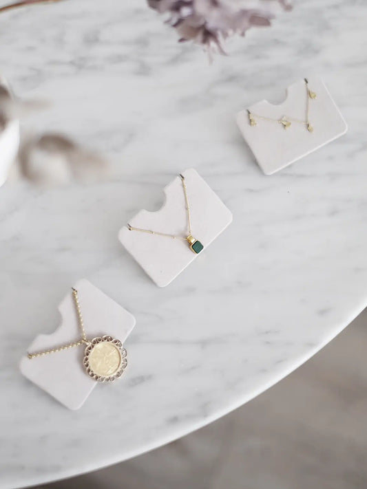 Three grey velvet Stackers pendant necklace holders displayed with necklaces on a marble surface. Jewellery not included.