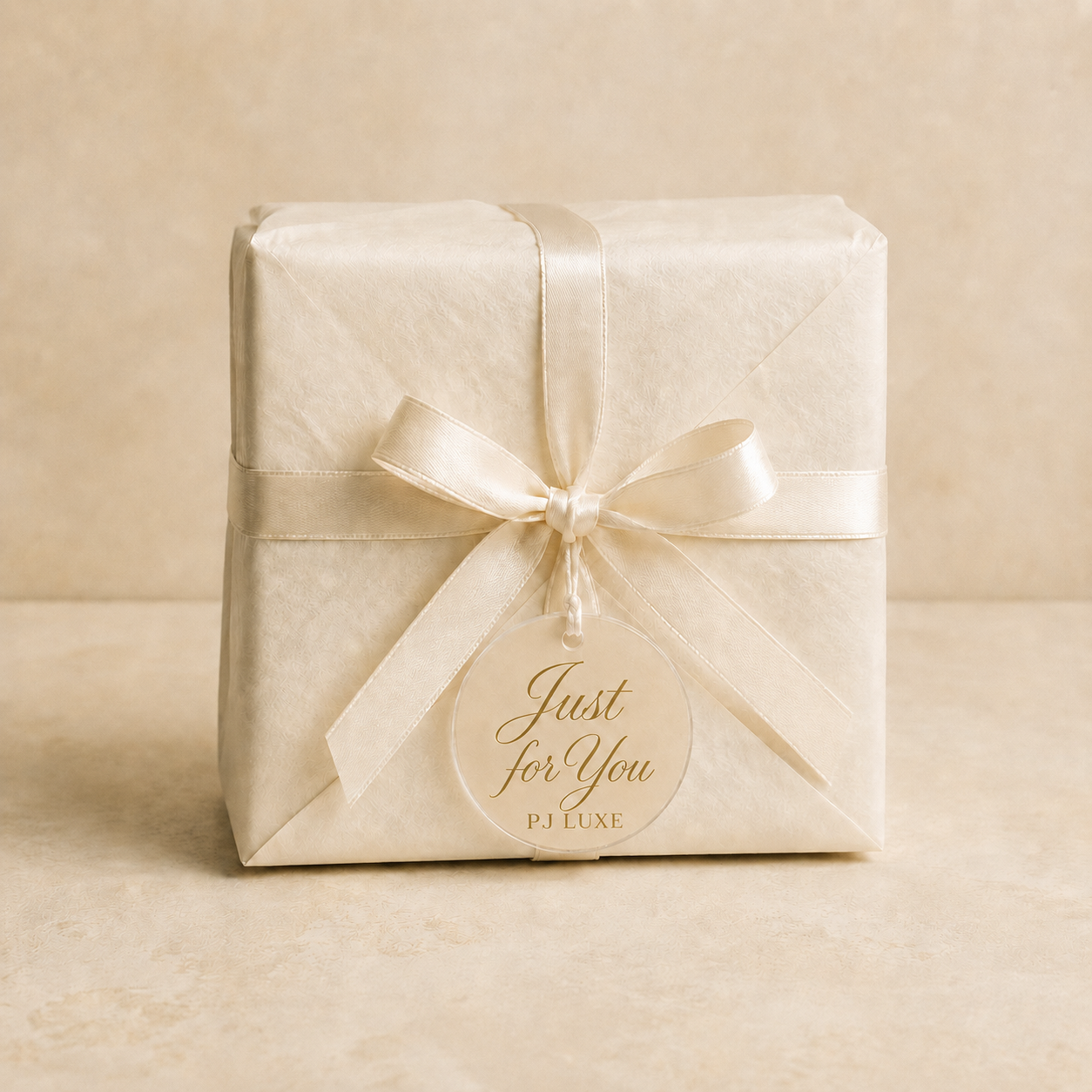 Optional PJ Luxe candle gift packaging with ivory tissue, cream ribbon and beige-backed acrylic tag with gold Just for You and PJ Luxe wording