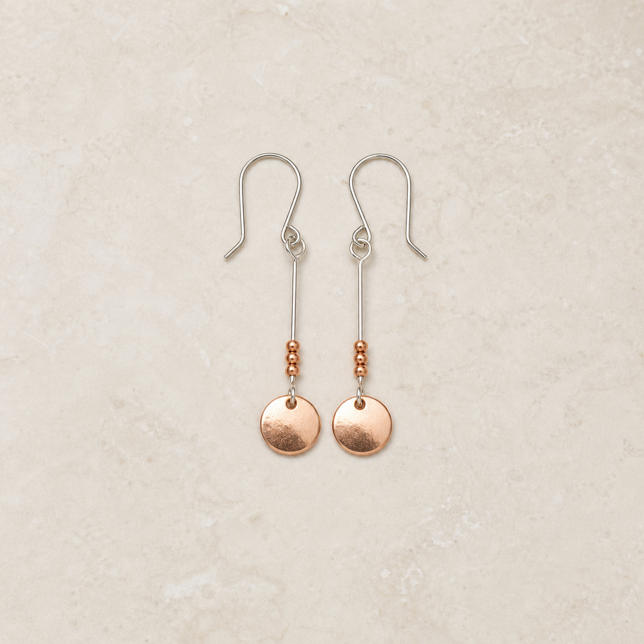 Copper and sterling silver dangle earrings on a warm ivory background