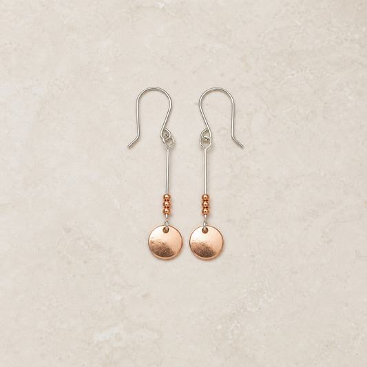 Copper and sterling silver dangle earrings on a warm ivory background