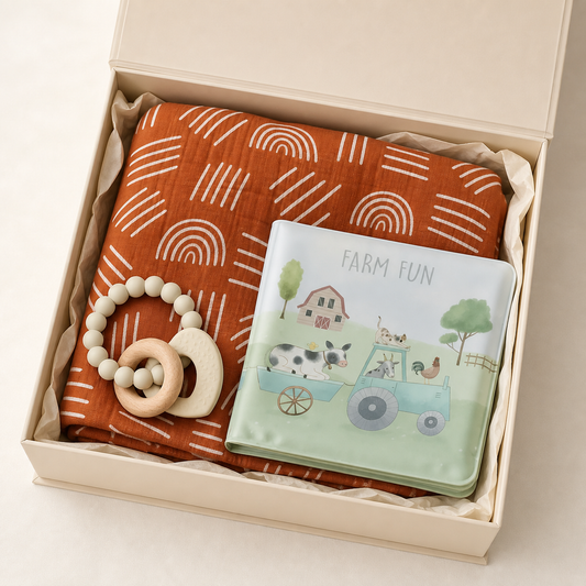 Muslin blanket, teether and bath book presented in an open ivory new baby gift box