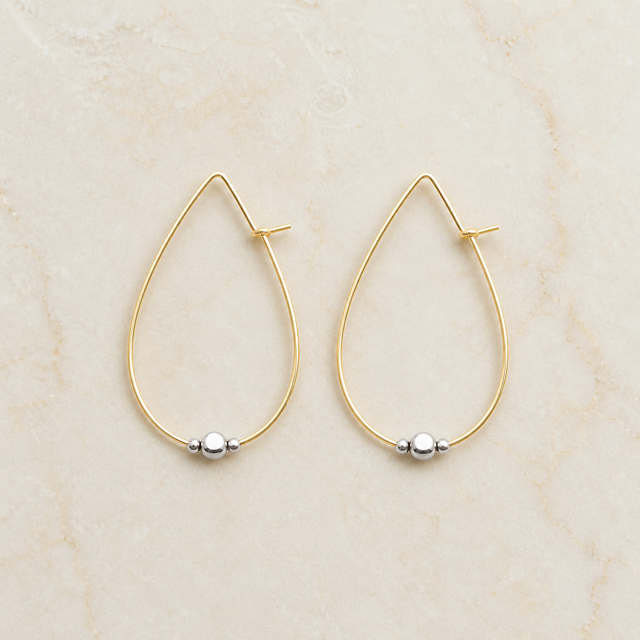 Gold-filled and sterling silver hoop earrings on a warm ivory background