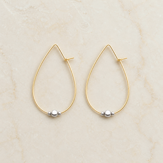 Gold-filled and sterling silver hoop earrings on a warm ivory background