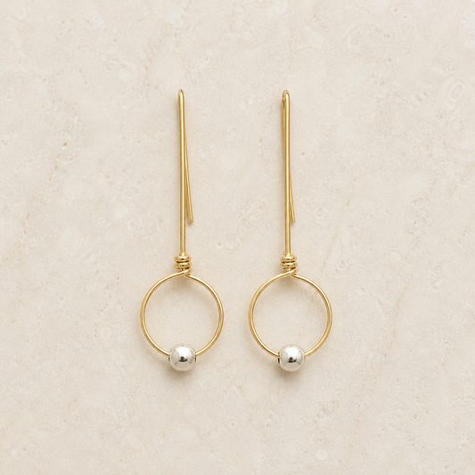 Gold-filled threader hoop earrings with silver beads on a warm ivory background