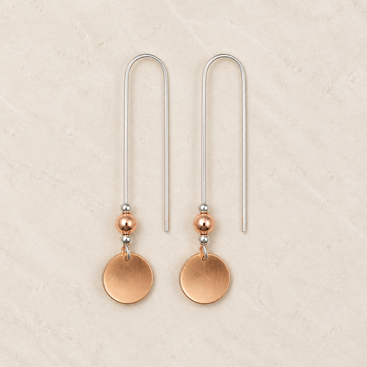 Sterling silver threader earrings with copper dangles on a warm ivory background