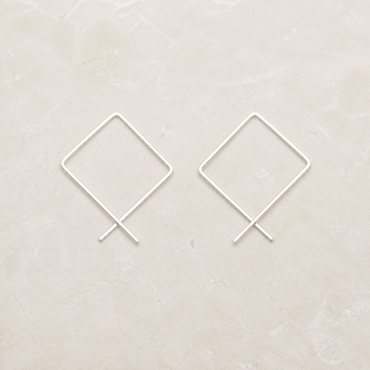 Sterling silver square threader hoop earrings on a warm ivory background